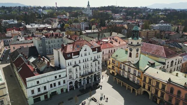 Aerial cinematic orbit view of the historic market square in Cieszyn, Poland. Drone circling the old town hall and historic hotel building.