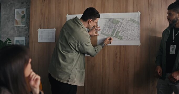 People gather in an office to discuss details shown on a map while taking notes and sharing ideas