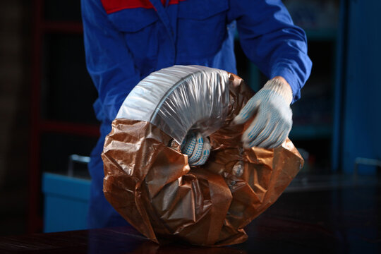 Worker packs finished bearing. Finished products at factory. Oiled parchment for packaging metal products. Workshop at heavy industry plant. Heavy industry