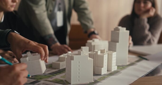 A group discusses and plans a community layout using scale models and maps in a meeting room during the afternoon