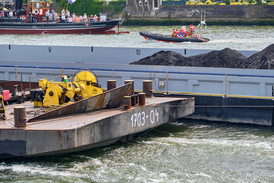 Dordrecht, Netherlands - 31 May 2026: View of a German self-propelled Rhine coal carrier pushing and towing barges on de Oude Maas river with a rescue boat in the background.