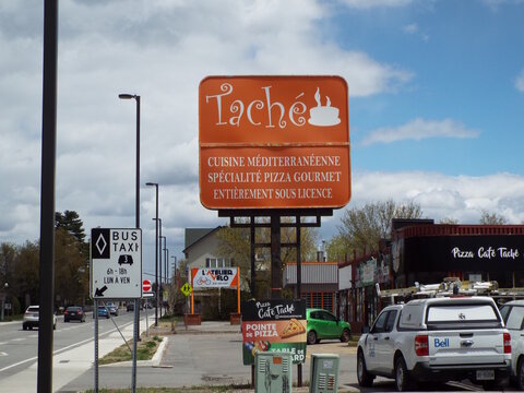 Gatineau, Quebec, Canada &ndash; May 8, 2026:A large orange sign advertises "Tach&eacute;" Mediterranean cuisine and gourmet pizza next to a street with cars on Boul. Alexandre-Tach&eacute;.