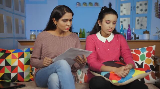 Angry Indian mother scolding her daughter for not concentrating on her - Mother and Daughter Relation. Medium shot of a strict mother annoyed with her teenage daughter for making mistakes in her ho...
