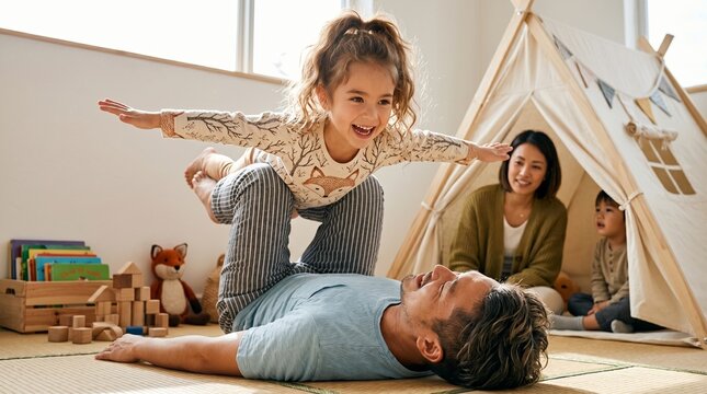 A happy young family, with mother, father and smiling little daughter, have fun and laugh together while building a fort inside their house