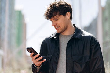 Happy young man using smartphone in modern city looking at screen © Maria Vitkovska