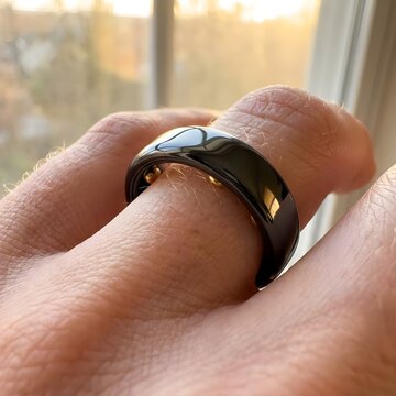 A person ' s hand holding a black ring