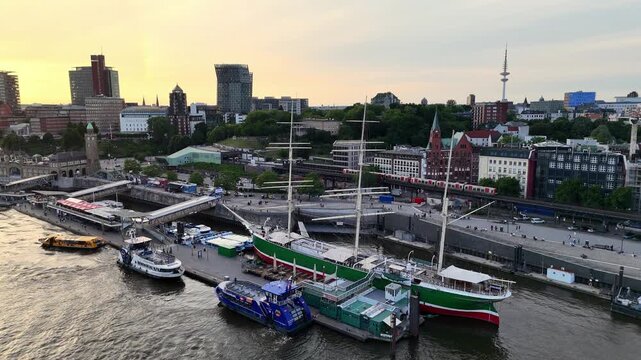 Hamburg, Germany - 02 June 2026: Aerial view of Landungsbrucken harbor with the Rickmer Rickmers sailing ship moored at the pier during sunset in Hamburg, Germany.