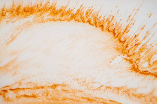 Bright orange paint spreads across a white surface creating a smooth texture and a warm feel