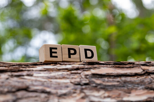 Wooden blocks with acronym EPD Environmental Product Declaration on tree bark. Sustainable manufacturing, green construction and eco certification concept