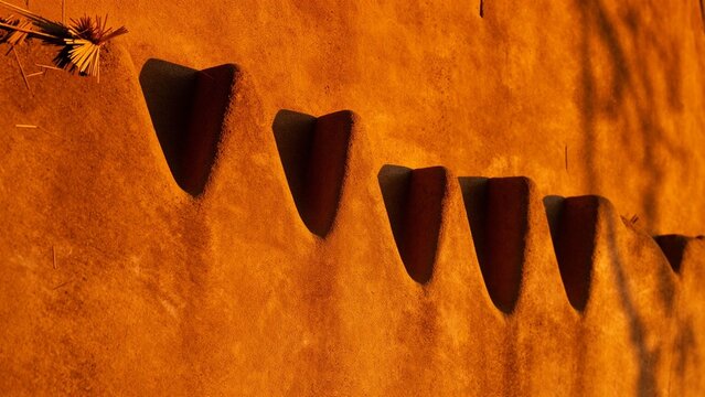 Close up view of traditional adobe mud wall with decorative carved architectural details in warm golden light