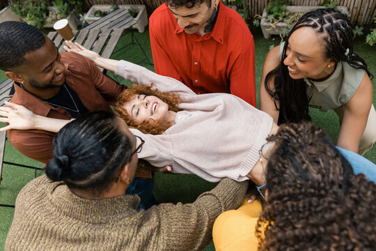 Diverse friends performing trust fall activity outdoors