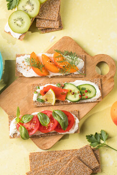 Fresh crunchy rye crispbreads with different toppings on green table, top view