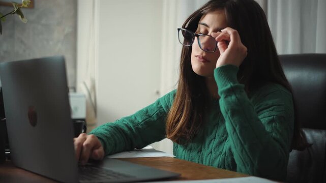Video of a young Hispanic woman finishing her workday at the office. Long working hours, exhaustion and workplace stress concept.
