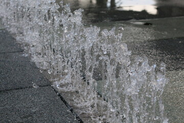 Close-up of water splashing and cascading over textured stone paving © khomkrit