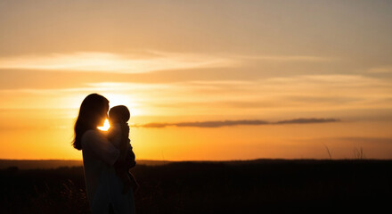 Fototapeta premium Mother holding baby silhouette during golden hour sunset in an open field representing family bonding and maternal care outdoor