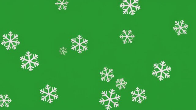 White snowflakes falling on a solid green background for winter holiday design isolated on a solid green screen chroma key background..