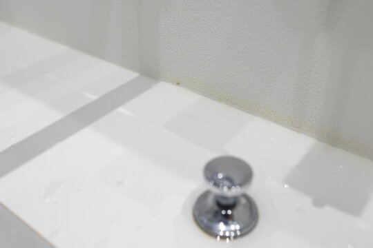 洗面所の角部分。壁クロスの黄ばんだ汚れと白いシンク