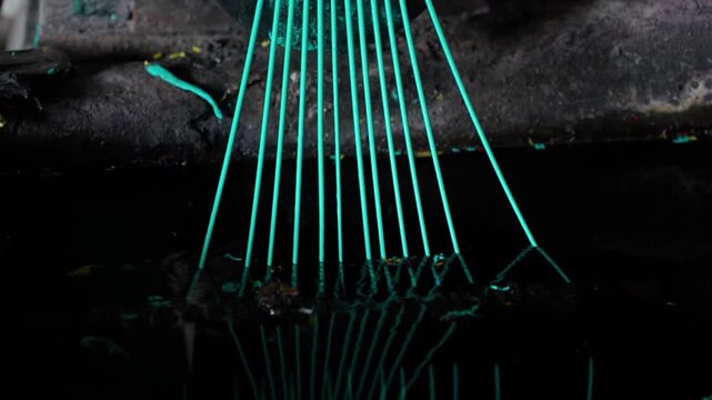 View of green plastic filaments being extruded from an industrial machine nozzle in Bogura, Rajshahi Division, Bangladesh.