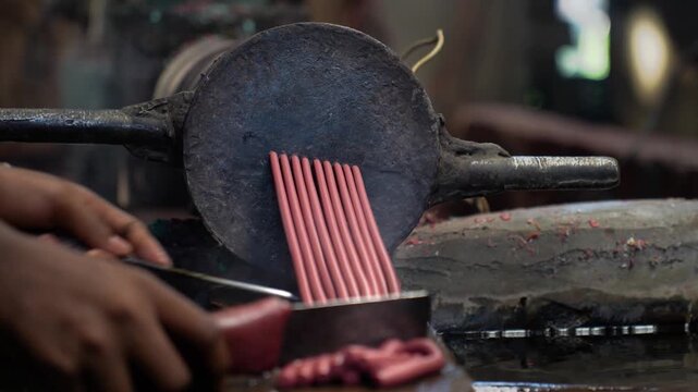 View of red plastic strands being extruded from a metallic machine in an industrial workshop in Bogura, Rajshahi Division, Bangladesh.
