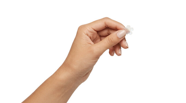 A close up of a woman hand holding a tiny white flower shaped paper confetti isolated on a solid black background, for celebration concepts