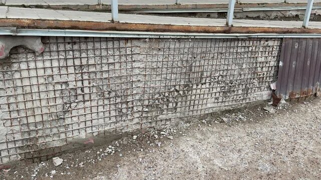 Rusty metal cladding and mesh on apartment extension showing heavy corrosion, flaking paint and exposed brick, twisted mesh