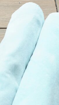 Vertical video: Tilting camera revealing poolside deck and tiles while showing blue fabric forms