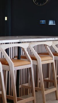 Vertical video: Panning camera showing marble island and four wooden stools in kitchen, glazed door