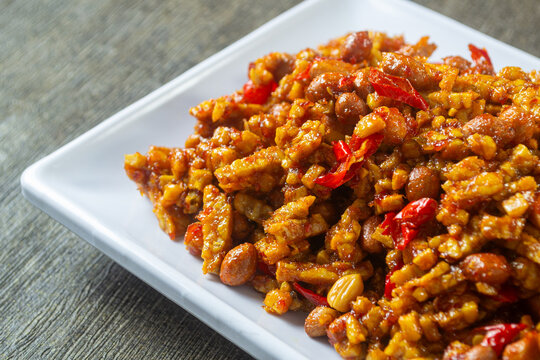 kering tempe served in white plate, Crispy caramelized tempeh strips with chili and peanuts garnish, traditional Indonesian food