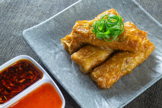 Homemade crispy lumpia kulit tahu, savory chicken and shrimp spring rolls in tofu skin, served with sauce and chili oil