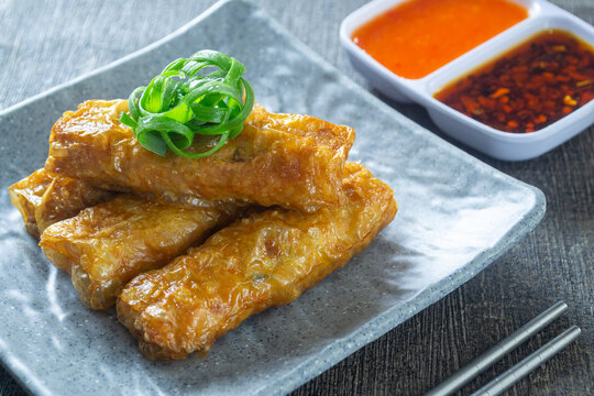 Homemade crispy lumpia kulit tahu, savory chicken and shrimp spring rolls in tofu skin, served with sauce and chili oil