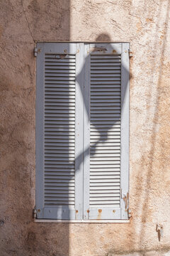 Weathered shutters cast shadow on rough stone wall, Biot