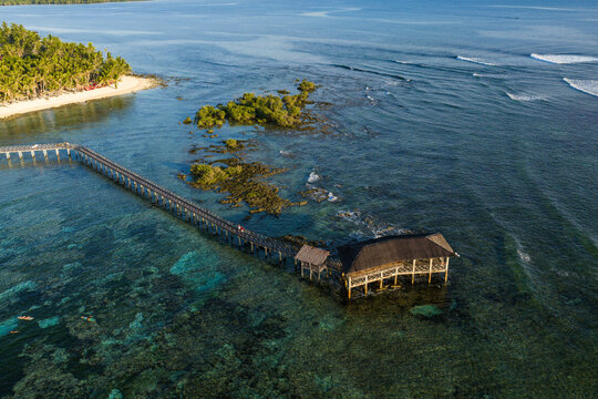 Aerial view of the iconic Cloud 9 boardwalk and pavilion over turquoise waters with coral reefs and breaking waves General Luna, Caraga, Philippines.