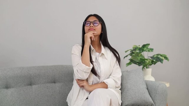 Thoughtful Young asian woman on sofa for thinking for an idea and a plan
