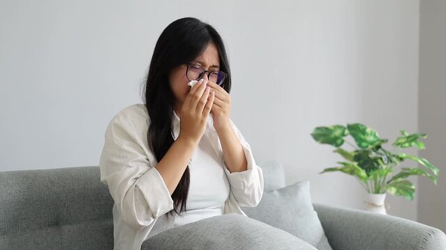 Young Asian Woman sick with blowing nose sneezing with tissue for infection