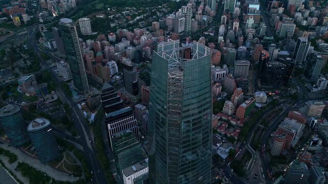 Retreating reveal rising over Costanera Center exposing vast Santiago urban sprawl, green parks, financial district and city limits fading to dusk horizon. Santiago, Chile