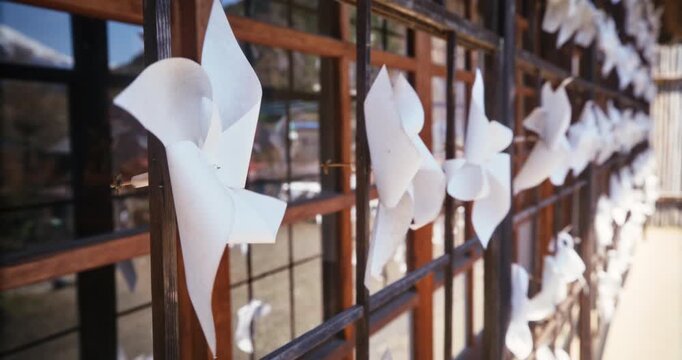 Closeup, steady cam shot on paper pinwheels spinning on wall of old Japanese structure