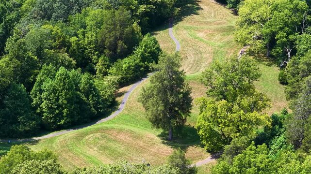 Green landscape with trees and road leading to a structure.