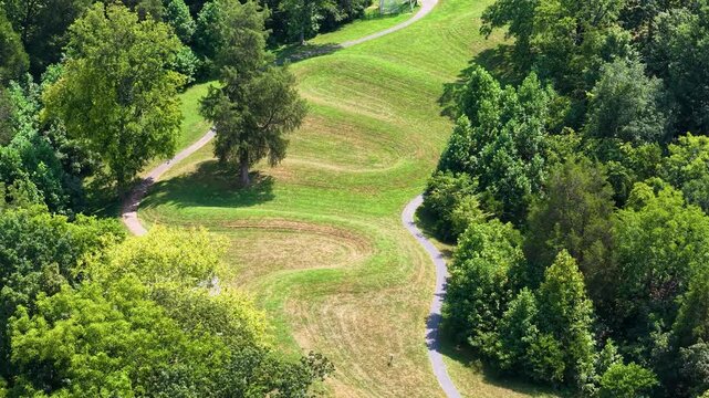 Aerial view of a serpent mound with trees and path in a grassy field.