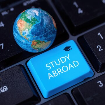 Blue paper cutout globe with study abroad text on laptop keyboard