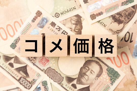 「コメ価格」と書かれたブロックとたくさんの一万円札