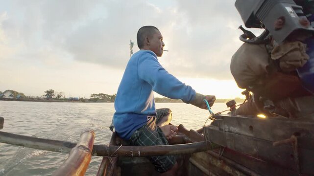 Indonesian fisherman on outrigger canoe with long-tail boat engine, traditional fishing boat in coastal village in indonesia, southeast asia, smoking
