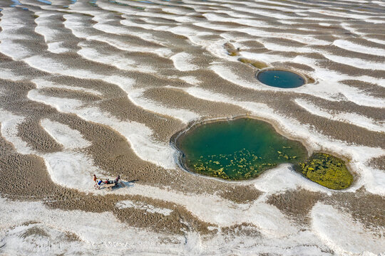 Aerial view of the Jamuna River Char showing unique sand ripple patterns and small green water pools with people pushing a cart Tangail District, Dhaka Division, Bangladesh.