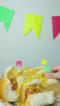 Sticking traditional mini Festa Junina flags into hot dogs