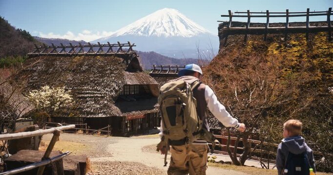 Father and son walking through old Japanese village with mt. fuji in the background, wide shot