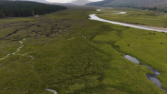 Aerial View of Winding River Through Green Highland Valley