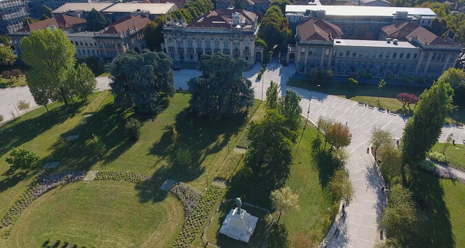Aerial view of the Politecnico di Milano campus featuring historic university buildings with red-tiled roofs, green lawns, and paved walkways in Milano, Lombardia, Italy.