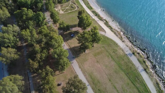 Aerial wide angle coastal forest park with runners and seaside path