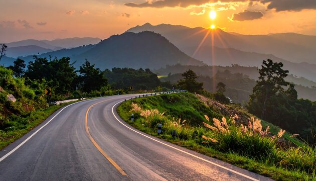 A winding road through lush hills at sunset, sunburst above distant mountains