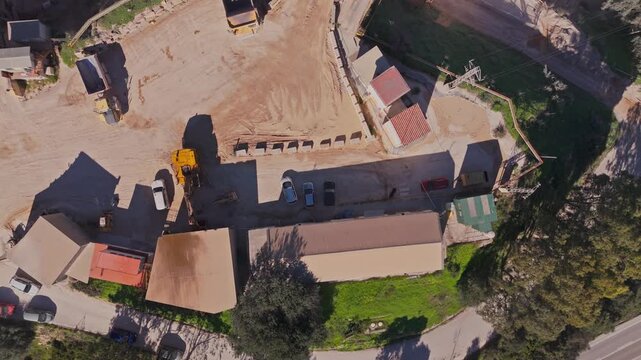 Aerial view of a stone quarry with a processing plant and asphalt plant featuring heavy machinery and trucks on dusty ground in Manilva, Andalusia, Spain.