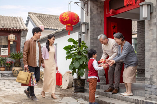 A young family with a child brings gifts to visit senior relatives at a traditional Chinese courtyard during Spring Festival.
